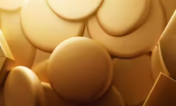 some golden round cookies are piled on a surface