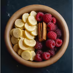 a bowl full of fruit and nuts on a black surface