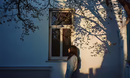 a woman in the shadows stands on the corner