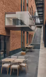 the outside of a brick building with wooden tables and chairs