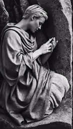 a young person sitting on a rock with their hands together