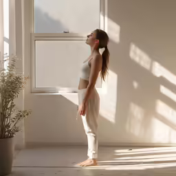 a woman standing in a room with the sunlight shining through a window
