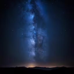 a man standing on top of a hill looking up at the night sky
