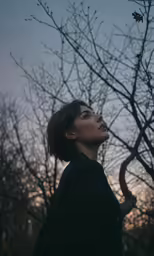 woman looking up into the sky surrounded by trees