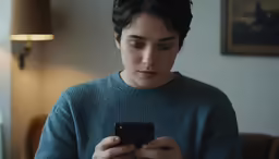 a woman standing in front of a light looking at her cell phone