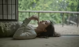 a young woman laying down on the floor in front of a window