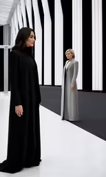 two women stand next to each other near large white structures