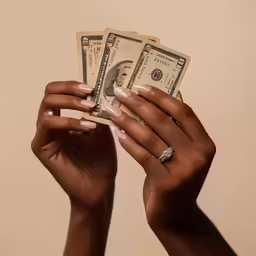 a woman holding two dollars in her hands