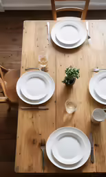 a long dining table has plates and cups on it