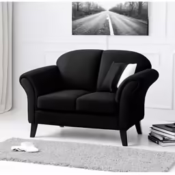 black sofa with black pillows sitting on carpet next to wall