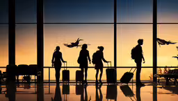 the silhouettes of people are walking through an airport terminal,three people standing near a large window with their luggage