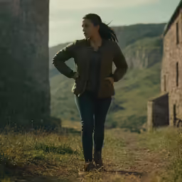 woman walking up a dirt road towards some buildings