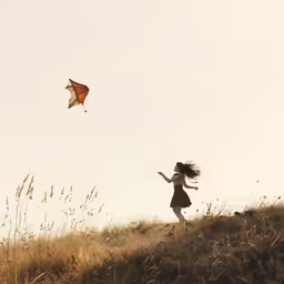 a woman is running with her kite on a grassy hill
