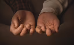 two hands folded over the top of a sofa