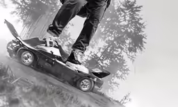 a person standing on the side of a hill while holding onto an upside down car
