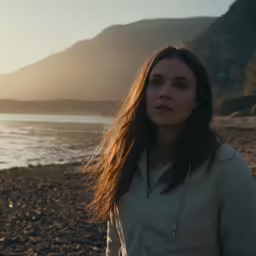 woman looking away on beach in front of mountain