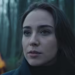 a woman with long hair standing in the woods