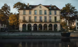a building with lots of windows and a lot of trees near the water