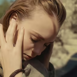 a woman is rubbing her eyes as she looks down