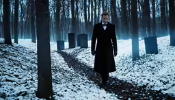 a man standing in a snowy forrest, wearing a coat