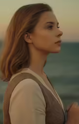 a woman standing in front of the ocean at dusk