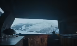 a view through a window into a snowy mountain