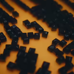 an array of black keyboard keys on a yellow table