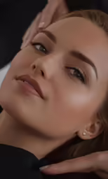 a woman with blonde hair and brown eyes is getting her makeup done