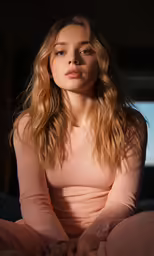 a woman with blond hair sitting on the bed