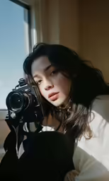 a girl in white shirt holding up a camera