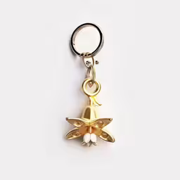 a gold charm with a bird on it,a golden bell charm on a key chain