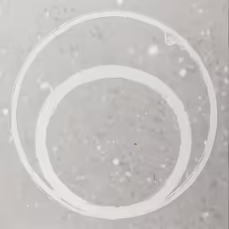 a white circle on a gray surface surrounded by white snow