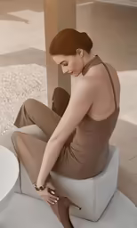 a woman in brown is sitting on a cement structure