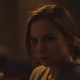 a young woman staring into the distance in a darkened room
