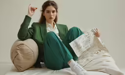 a woman sitting on a bed holding a sheet of paper