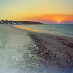 a sandy beach at sunset with the sun shining in the distance