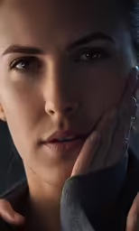 an attractive woman with dark makeup holding her chin