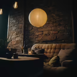 a dimly lit room with stone walls, a couch and a round table