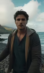a young man standing on top of a rocky beach