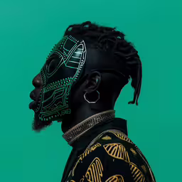 a black man with dreads and a green painted mask on,the man wearing the black mask has bright green designs on his face