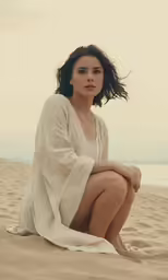 a woman sitting on top of a sandy beach