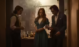 a woman and two men standing next to each other in a kitchen