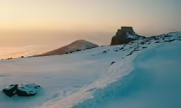 a snow covered mountain next to the ocean