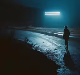 a person walking towards an open area on a dark street