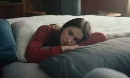 a young woman sits on top of a white bed