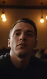 a man wearing a black t - shirt looking off to his right