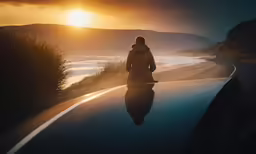 someone sits on top of a car as the sun sets