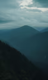 mountain scenery from top of a hill under cloudy sky