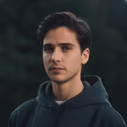 a young man in black hoodie posing for a photo