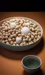 a bowl of nuts and two bowls of soup sit on a counter